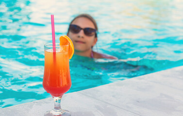 Woman in the pool with a cocktail. Selective focus.