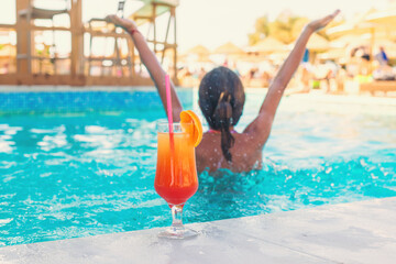 Woman in the pool with a cocktail. Selective focus.