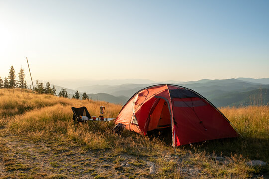 Summer Pamporovo Bulgaria aerial sunset view, red tent glowing on mountain meadow, golden light across hills, outdoor adventure travel destination in Balkan mountains, serene tourism nature scene. - Powered by Adobe