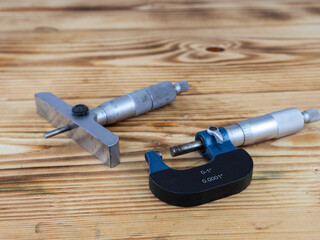 A comprehensive display of precision measuring tools, including a depth micrometer and an external micrometer on wooden surface.