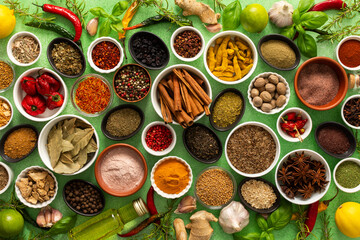 A colorful assortment of fresh, fragrant spices and herbs displayed on a soft green background, capturing a vibrant culinary essence