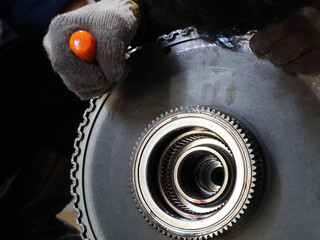 Close-up mechanic's hands working on a large, remove the retaining ring with a screwdriver....