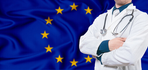 European Union healthcare concept. Male doctor on European Union flag. Doctor with crossed arms on...