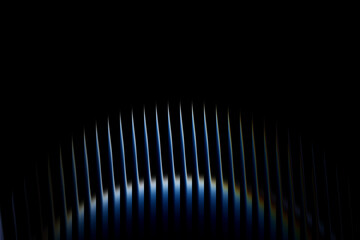 Abstract close up of a modern microphone grill with striking blue and white light reflections