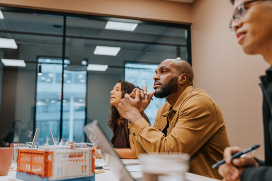 Focused bald male entrepreneur listening to ideas shared in meeting at office