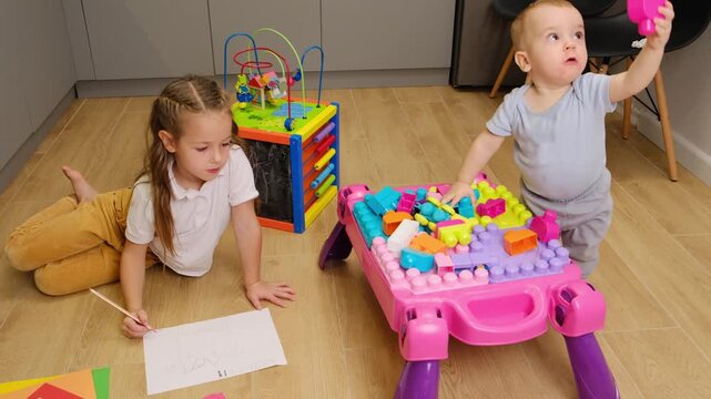 Two cute sibling children girl and boy playing in kitchen room. toddler make first step without help. Preschool education.