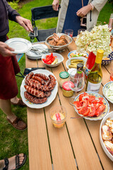 piknik w ogrodzie, tradycyjny stół z wędlinami, kiełbaskami i sałatkami winem i dodatkami. spotkani towarzyskie