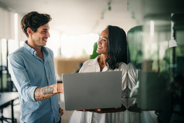 Two happy diverse multiethnic business team people working, talking in corporate office
