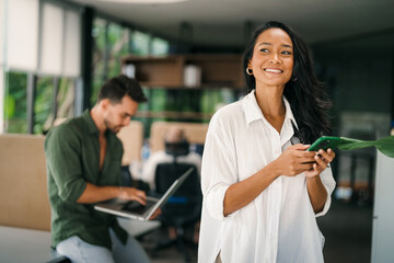 Naklejka na ściany i meble Busy smiling executive business team using digital devices in office. Diverse professional people