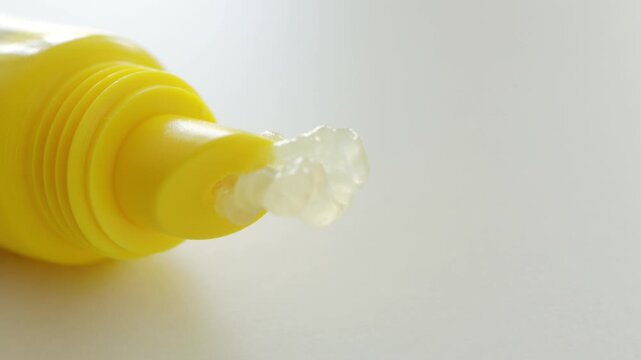 Yellow tube with transparent lip balm squeeze. Skincare beauty product texture macro