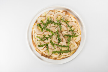 Gourmet flatbread topped with thinly sliced apples, arugula, and blue cheese, presented on a white plate, showcasing a modern culinary creation with vibrant colors