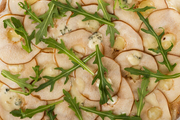 Thinly sliced meat arranged beautifully with creamy cheese and fresh arugula, creating a visually appealing gourmet dish perfect for culinary presentations and food photography