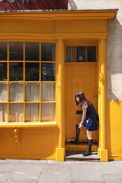 Side view of teenage girl pulling up stockings while outside door at street