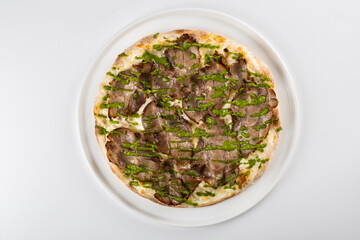 Gourmet pizza topped with tender beef slices and fresh green asparagus drizzled with savory sauce...