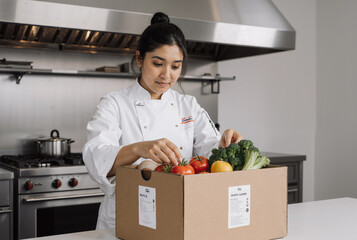 young chef inspecting fresh vegetables in a professional kitchen, ensuring quality for culinary preparation