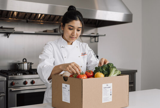 young chef inspecting fresh vegetables in a professional kitchen, ensuring quality for culinary preparation