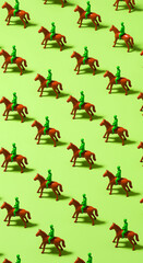 A repeating pattern of small toy horses and jockeys in green riding outfits on a light green background creating a whimsical and playful visual