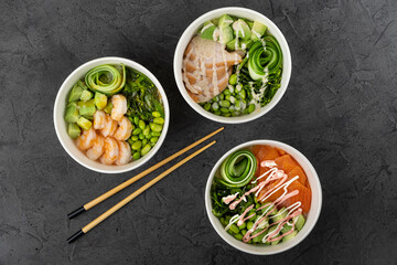 Three bowls of vibrant sushi with shrimp, salmon, and vegetables arranged artistically on a dark textured surface, showcasing fresh ingredients and culinary creativity