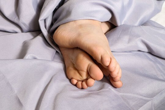 Bare feet of a sleeping child on a gray background