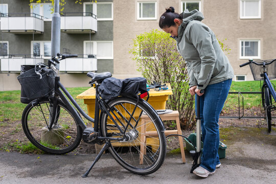 Full length of woman pumping air in cycle tire - Powered by Adobe