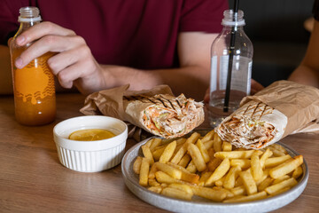 Delicious wraps filled with fresh ingredients served alongside crispy golden fries and a dipping...