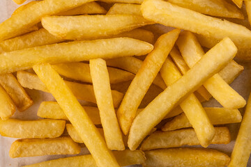 Golden crispy French fries arranged in a casual overlapping pattern on a light background, showcasing their delicious texture and appealing appearance for culinary presentations