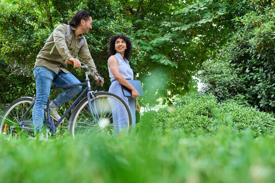 Colleagues walking and cycling in park discussing projects