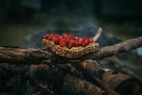 Wild strawberries on slice of bread cooking over firewood