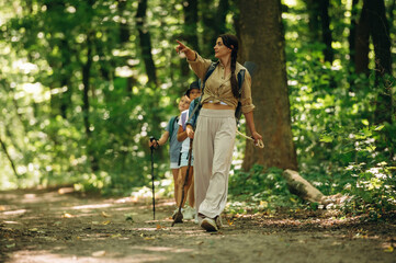 Fototapeta premium Hand gesture, showing something, pointing at. Woman is doing tour for group of kids in the forest