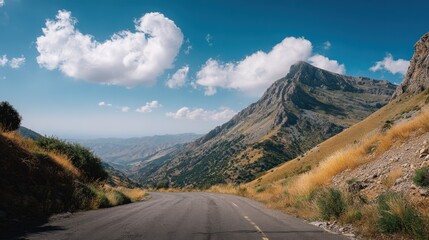 Fototapeta premium Scenic Mountain Road Under a Bright Blue Sky with White Clouds, High-Angle View