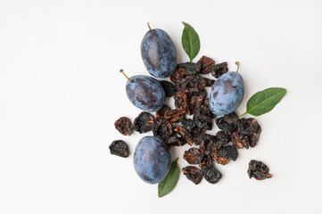 Dried plum prunes and fresh plums with green leaves on gray background flat lay top view. Food background, dried delicious fruits, sweet healthy dessert, healthy eating