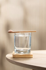 A spoon of Himalayan salt is being added to a glass of drinking water.