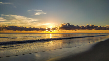 The peaceful waves of Bainema Beach reflect the last rays of sunshine as the sun sets on Boipeba...
