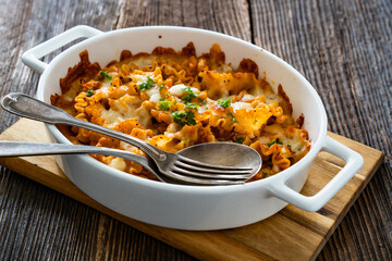 Pasta casserole with marinara sauce and mozzarella cheese on wooden table