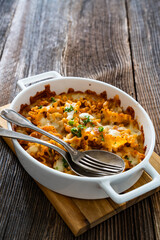 Pasta casserole with marinara sauce and mozzarella cheese on wooden table