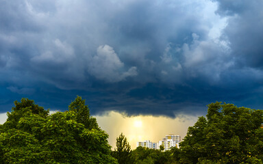 Ominous thunderclouds over landscape with trees and city buildings