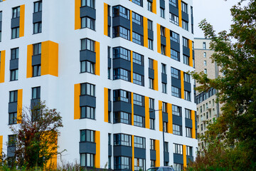 A modern building with white facades and bright orange accents. Rectangular windows, clear lines...