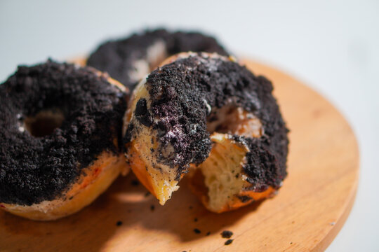 Closeup. Three chocolate donuts with oreo topping on a wooden stand