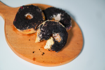 Three chocolate donuts with oreo topping on a wooden stand
