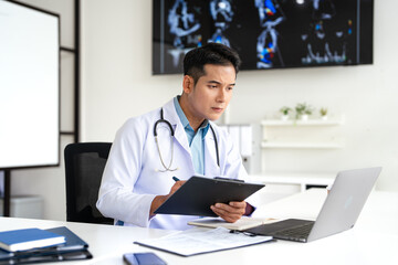 Fototapeta premium Doctor working in medical office using laptop computer and writing or taking note in notebook.