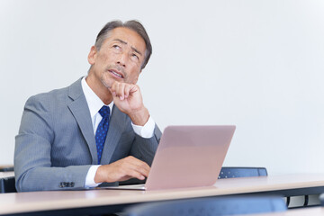 パソコンを見て考えるシニアビジネスマン