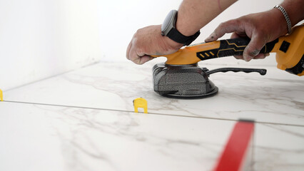 Construction worker placing marble tiles with tile leveling system
