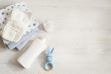 Baby care essentials with diaper, lotion and toy on wooden background