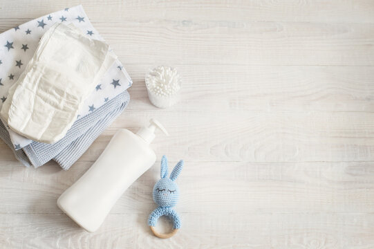 Baby care essentials with diaper, lotion and toy on wooden background - Powered by Adobe