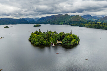 Kayaks on Derwentwater lake below a dramatic cloudy sky and mountains