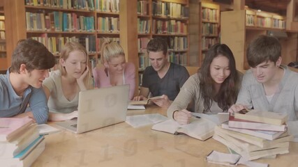 Animation of binary code over multiracial students studying with books and laptop in library - Powered by Adobe