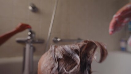 Mother styling toddler’s wet hair into playful punk shape with shampoo foam during bath time, happy child smiling, fun and intimate family bonding moment at home