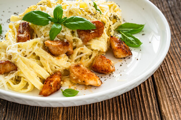 Classic creamy chicken alfredo fettuccine pasta on wooden table	