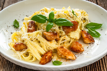 Classic creamy chicken alfredo fettuccine pasta on wooden table	