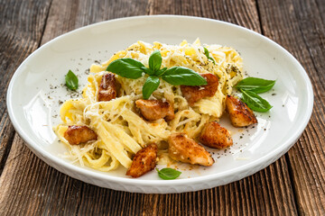 Classic creamy chicken alfredo fettuccine pasta on wooden table	